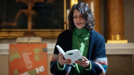 Nahaufnahme einer Person, die aus einem Buch liest, unscharfer Blick auf den Innenraum der Auferstehungskirche.