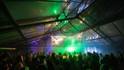 Tanzende Gäste im festlich beleuchteten Gewächshaus mit DJ, Lichtern und Discokugeln beim Festgartenfest.