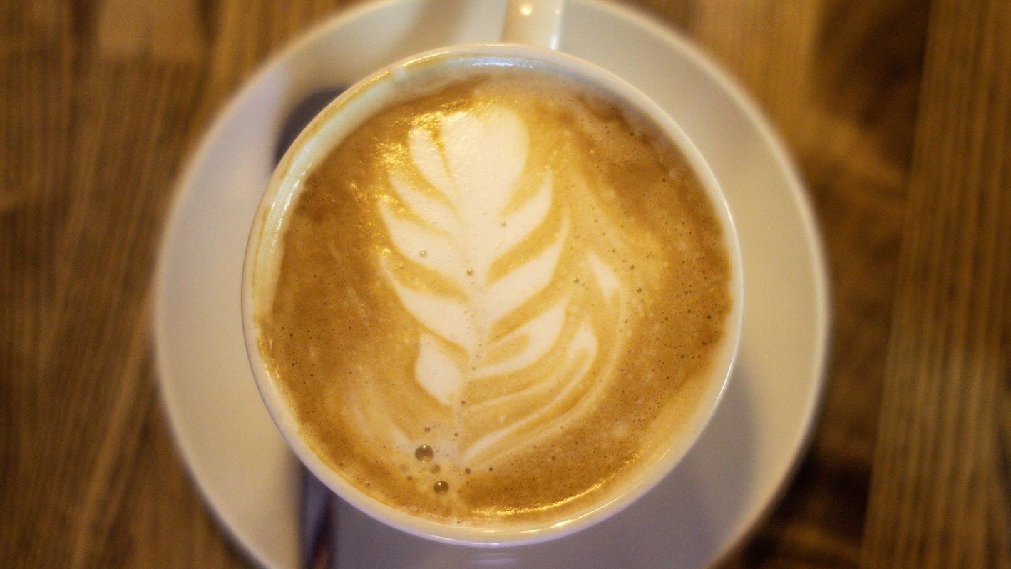 Eine Kaffeetasse aus dem Inklusionscafé Samocca mit kunstvollem Milchschaumbild.