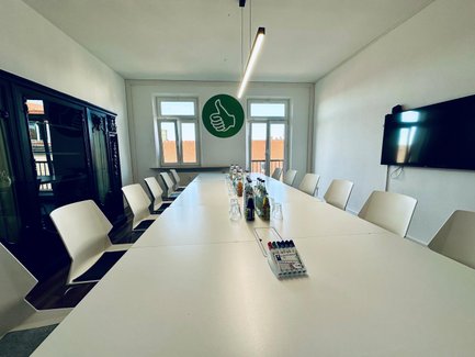 Seminarraum Fürth mit Konferenztisch, Stühlen, Apple TV und Getränken für Besprechungen