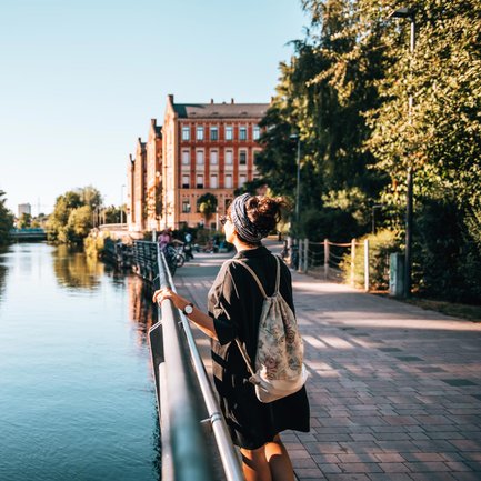 Eine junge Frau genießt den sonnigen Tag an der Fürther Uferpromenade und blickt zu den kißkaltschen Häusern