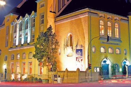 Außenansicht des Berolzheimerianum in Fürth mit gelber Fassade und Beleuchtung bei Nacht