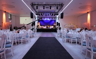 Festlich gedeckte Tische im First Class Event Fürth mit Blick auf Bühne, Technik und stimmungsvolle Beleuchtung