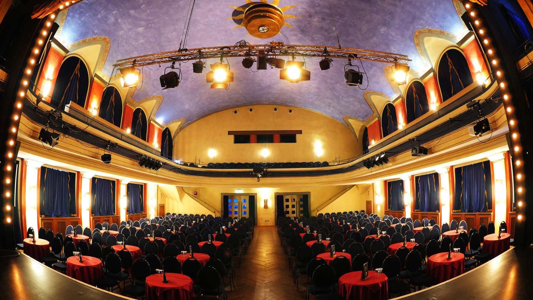 Innenansicht der Comödie Fürth: Bühne, Bestuhlung, Tische und stimmungsvolles Licht im Saal