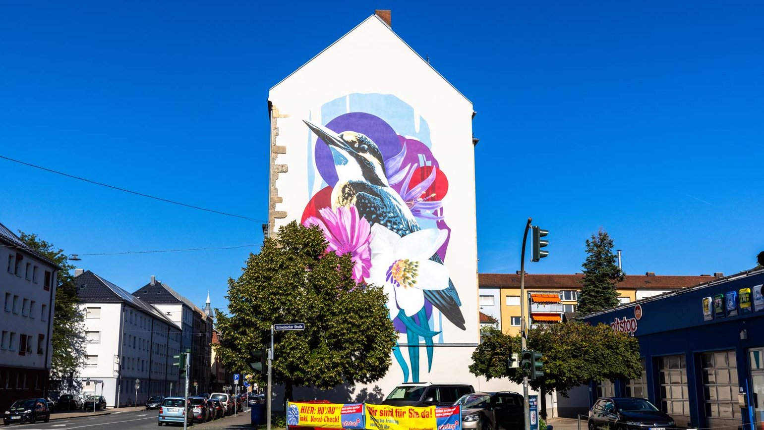 Hauswand mit großem Mural zeigt einen Vogel zwischen rosa und lila Blumen in Fürth.