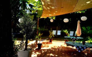 Sonniger Außenbereich des Alten Forsthauses in Fürth mit karierten Tischdecken Lampions und entspannter Atmosphäre