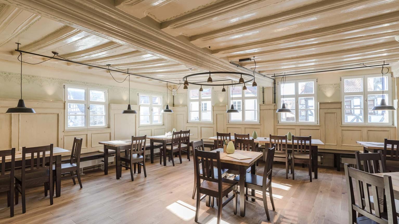 Heller, schlichter Gastraum im Grünen Baum mit verschiedenen Tischen und rustikalen Sitzmöglichkeiten