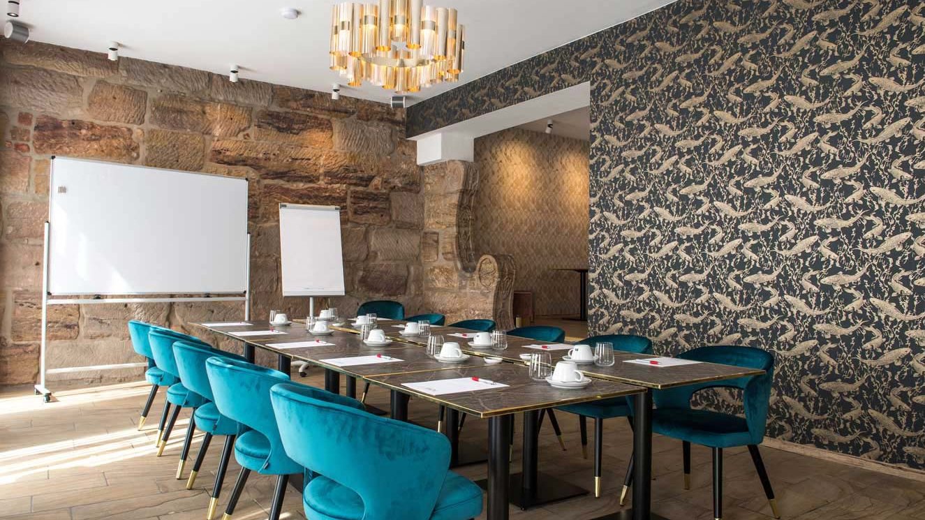 Hochwertiger Tagungsraum im Werners Hotel mit Sandsteinwand, edlen Stühlen und Tischen mit Blöcken.