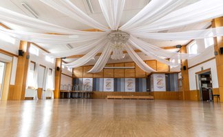 Große leere Eventhalle in Burgfarrnbach mit Kronleuchter und weißen Stoffhussen an der Decke