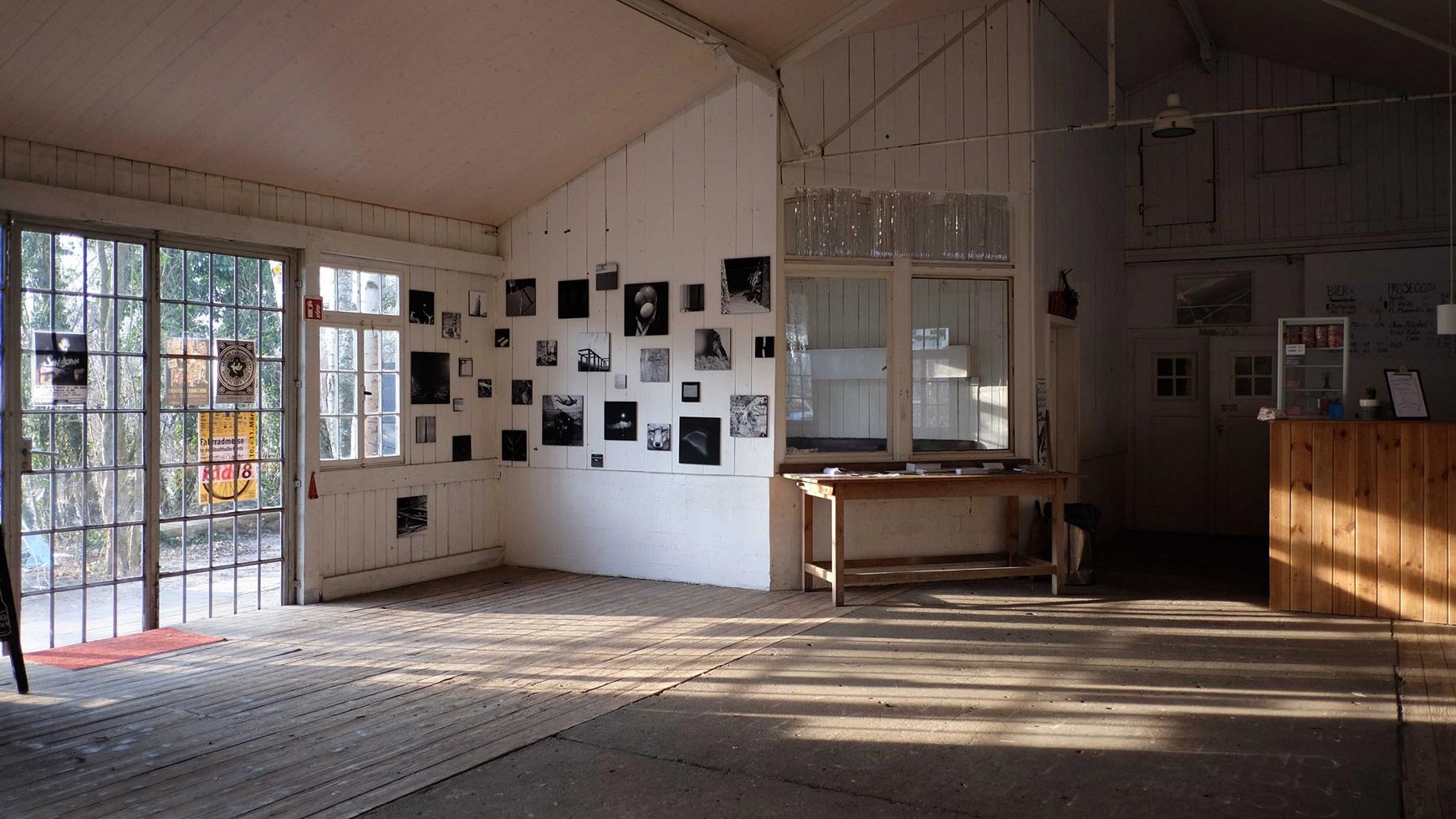 Kleine Fotoausstellung an der Wand, mit Aussicht auf Garten durch große Terrassentüren.