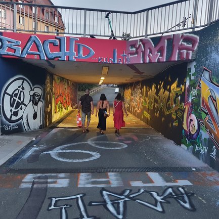 Drei Personen laufen durch die Graffiti-Hall der Julius-Hirsch-Halle in Fürth mit Public Enemy Kunst