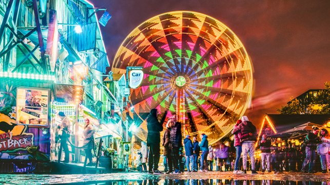 Abendstimmung auf der Michaelis-Kirchweih mit leuchtendem Riesenrad, Buden und schlendernden Besuchern