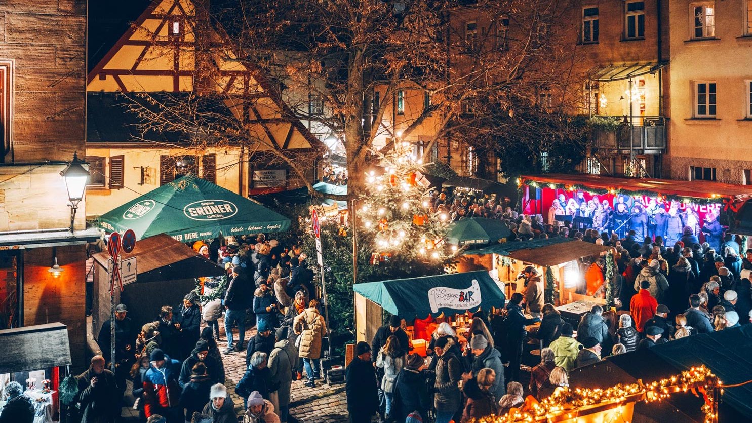 Die Altstadtweihnacht auf dem Waagplatz in Fürth, mit Weihnachtsbaum und dem beleuchteten Rathaus im Hintergrund.
