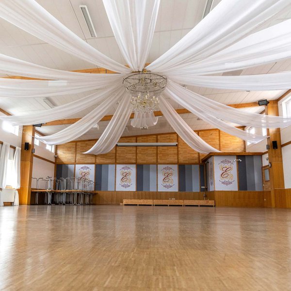 Große leere Eventhalle in Burgfarrnbach mit Kronleuchter und weißen Stoffhussen an der Decke