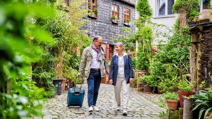 Zwei Touristen gehen durch die Fürther Pfarrgasse, ein Mann zieht einen Rollkoffer und spricht mit der Frau