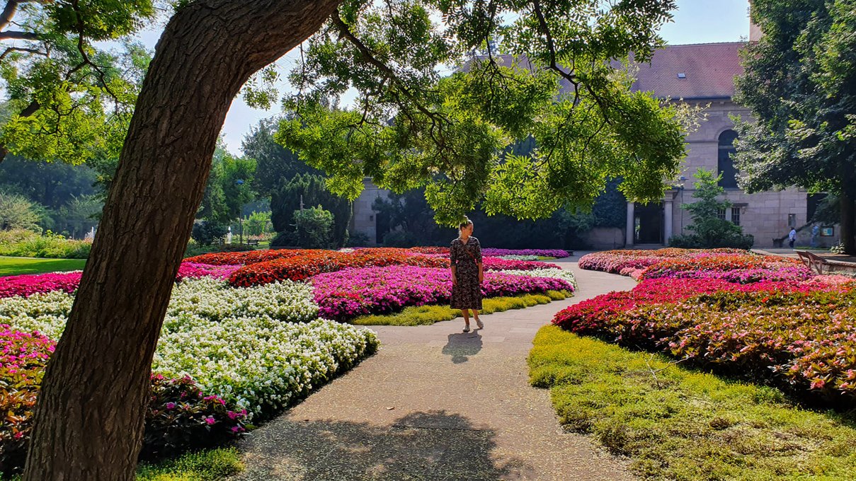 Sommerlicher Spaziergang durch den Fürther Stadtpark mit bunten Blumen und Kirche im Hintergrund.