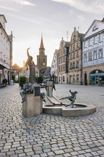 Gauklerbrunnen auf dem Grünen Markt in Fürth, im Hintergrund die Kirche St. Michael und Altstadthäuser.