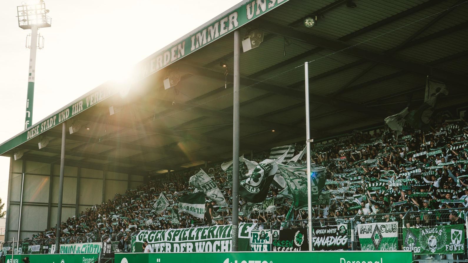 Die Nordtribüne bebt: Kleeblattfans halten Schals hoch und singen ihre Hymne im Abendlicht.