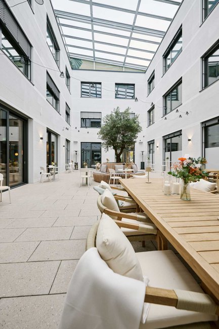 Atrium des Café Seasons in Fürth mit Glasüberdachung hellen Holztischen und großzügigen Sitzplätzen
