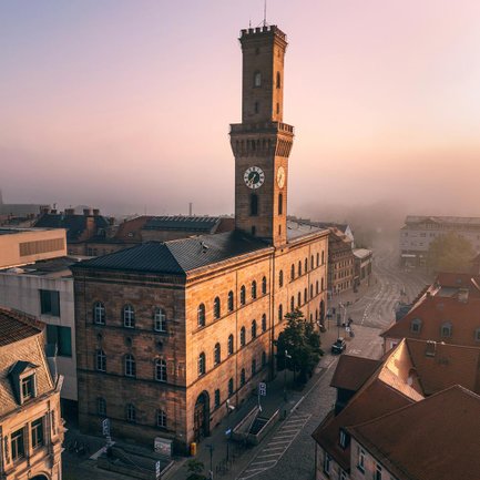 Die Abendsonne beleuchtet die Fassade des Fürther Rathauses, während die Altstadt in dichtem Nebel liegt