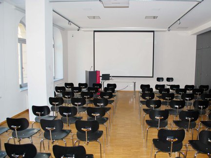 Reihenbestuhlung im Tagungsraum des Stadtmuseums Fürth, vorne Pult und große weiße Leinwand