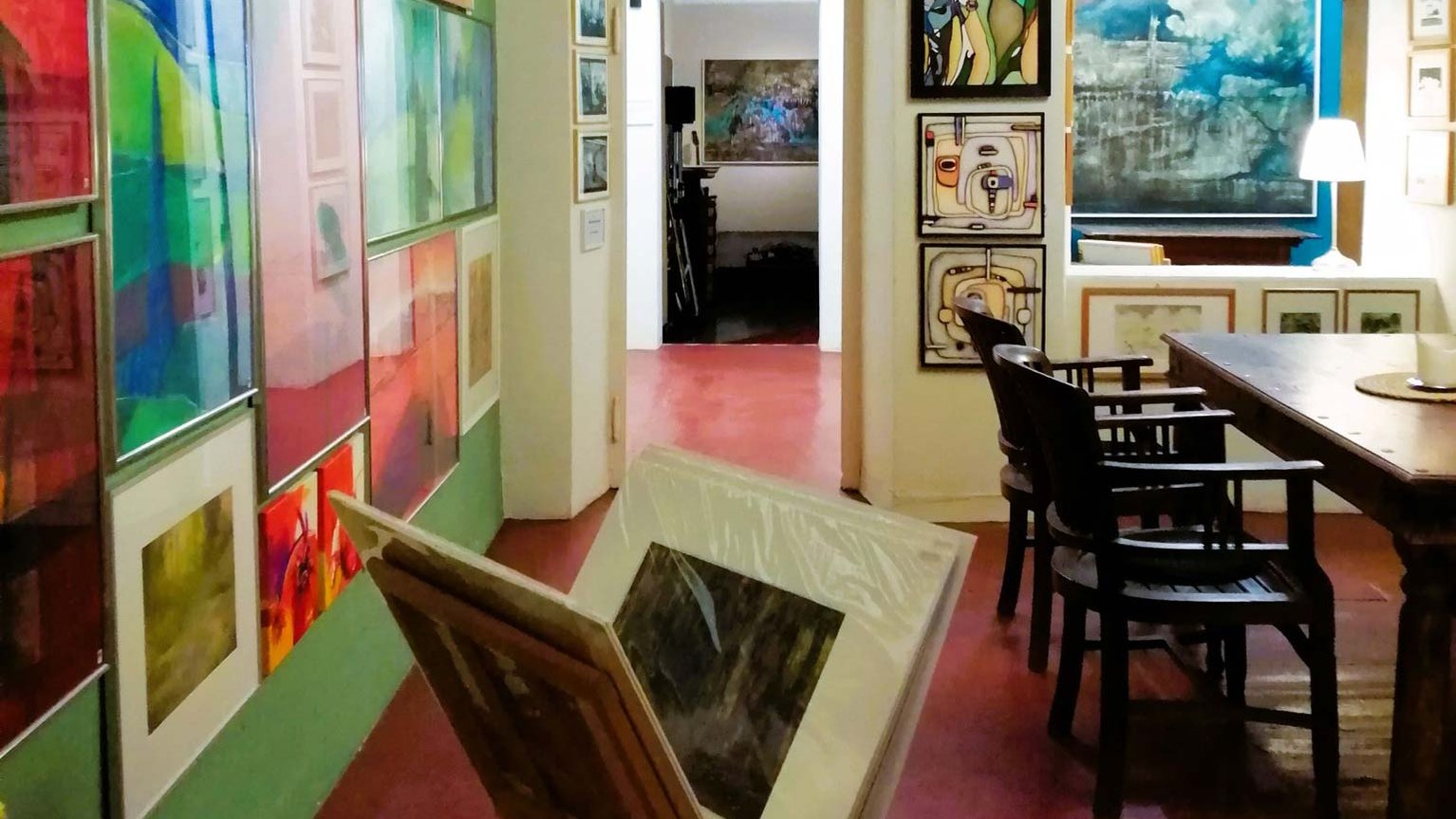 Bunter Raum im Kaltscher voller Kunstwerke mit einem zentralen Tisch und Stühlen in inspirierender Atmosphäre