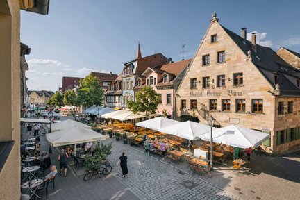 Blick auf die Gustavstraße in Fürth mit Restaurants, Bars, Cafés und historischen Häusern bei Sonnenschein.