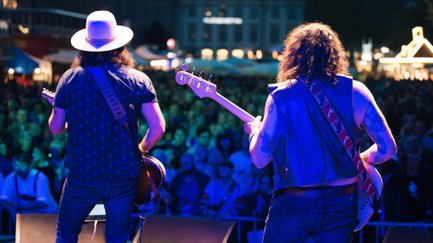 Zwei Gitarristen auf der Bühne, dahinter unscharf das Publikum auf der Fürther Freiheit beim Festival.