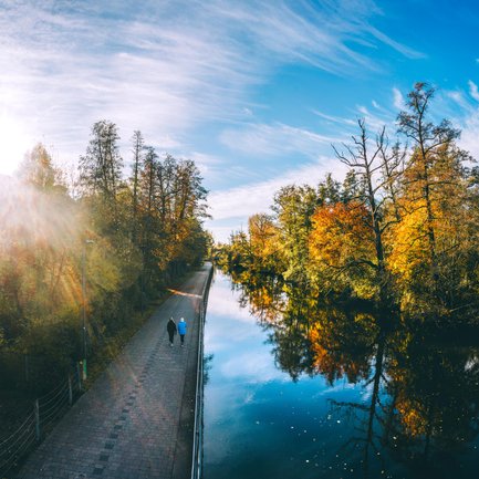 Sonniger Herbsttag an der Fürther Uferpromenade mit zwei Spaziergängern und goldenen Bäumen