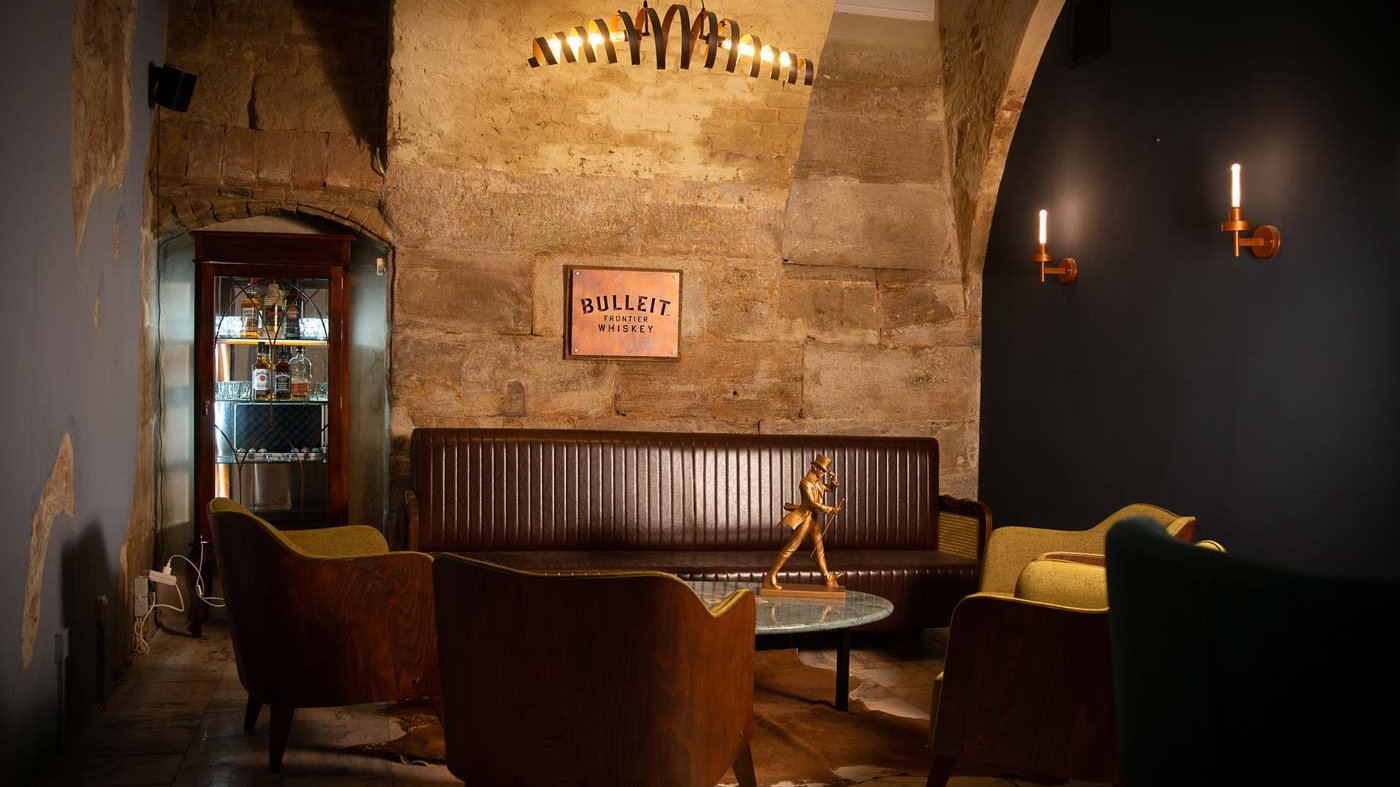 Innenbereich von Castros Bar mit Sandsteingewölbe, gedämmtem Licht, Whiskeyregal und Dekoration