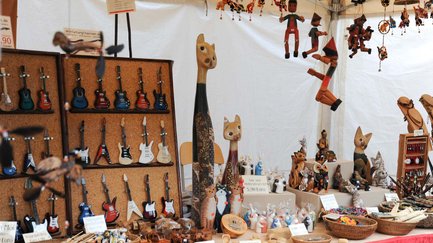Vielfalt an Holzkunst, Mini-Gitarren und Marionetten auf dem Marktstand des Gartenmarkts.