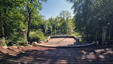 Blick von den hölzernen Zuschauerrängen auf die leere Freilichtbühne im grünen Fürther Stadtpark.