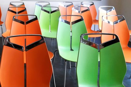 Reihen von grünen und orangefarbenen Stühlen im Kaltscher Fürth für Besucher und Veranstaltungen