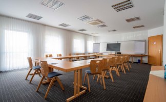 Heller Tagungsraum im Landhotel Seerose mit Holztischen, Stühlen, großem Bildschirm und Tischen mit Block und Stift