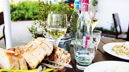 Wein, Brotkorb und zwei Spaghetti-Portionen mit Parmesan stehen als stimmungsvolles Arrangement beim Weinfest auf dem Tisch.