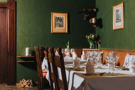 Gedeckte Tische im Hotel Forsthaus Fürth mit Holzstühlen, Blumen, gefalteten Servietten und grüner Tapete