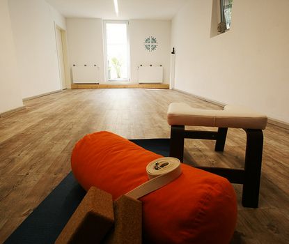 Yogaraum_Matilde Blick auf den Yogaraum mit Kissen, Stühlen und weiterem Equipment.