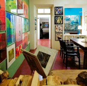 Das Kaltscher_2 Blick in die Räumlichkeiten des Kaltscher Fürth. An der Wand hängen viele bunte Bilder. Es ist ein Tisch mit schwarzen Stühlen zu sehen.