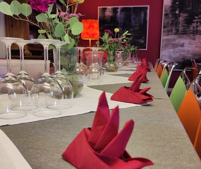 Das Kaltscher Eingedeckter Tisch mit Blumen und kunstvoll gefalteten roten Servietten im Kaltscher