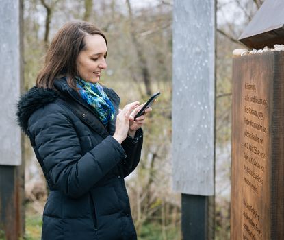Eine Frau steht rätselnd vor einem Pylon an der Uferpromenade in Fürth.