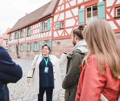 Höfe Eine Stadtführerin erklärt einer Gruppe von Touristen die verschiedenen Gebäude und Höfe der Fürther Altstadt. Im Hintergrund ist ein Fachwerkhaus.