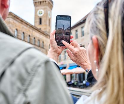 Touristen Ein Mann und eine Frau machen ein Foto von dem Fürther Rathaus mit ihrem Smartphone. Dabei ist das Handy und der Rathausturm im Vordergrund.