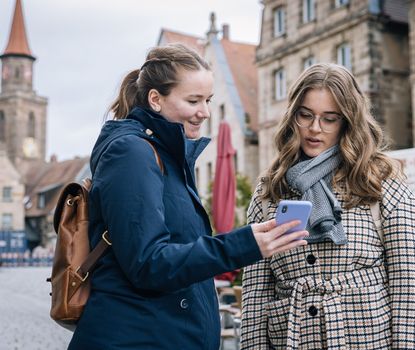 Zwei Frauen schauen in das Handy um ein Rätsel der Schnitzeljagd-App