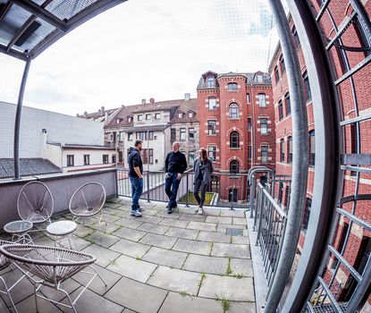 Workin3 Blick auf die Terasse des WorkIn. Im Hintergrund sind Altbauten und rote Backsteingebäude zu sehen.