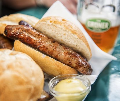 Bratwurst in Semmel Bratwurst in Semmel neben einem Glas Bier.