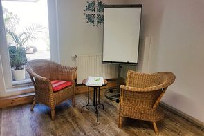 Matilde_2 Zwei Korbstühle sind um einen Tisch und ein Whiteboard ausgerichtet.