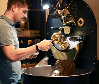 Kaffeesurium Ein Mann mahlt Kaffee an einer speziellen Maschine.