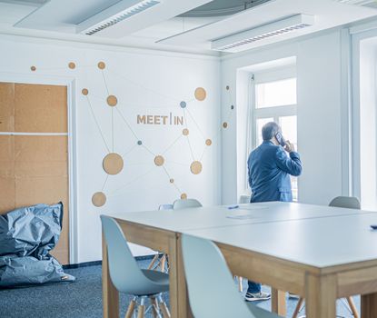 Workin2 Zu sehen ist ein Mann der in den Coworkingspaces arbeitet. Er spricht in sein Mobiltelefon.